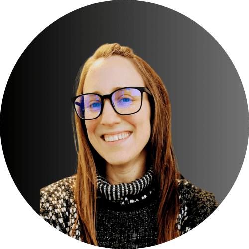 Woman with long reddish-brown hair and black-framed glasses wearing a sparkly black and white top, smiling at camera against gray circular background